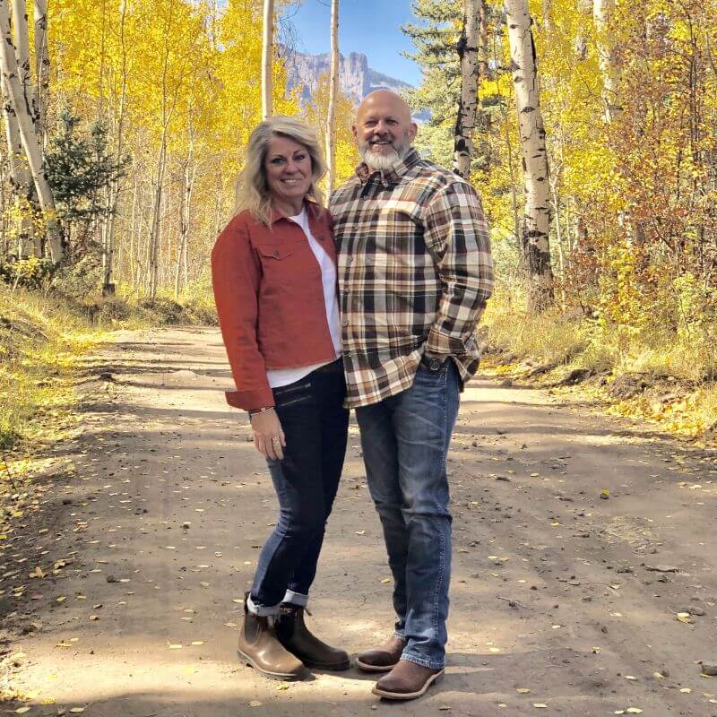 Larry and Gayla Nelson in front of a fall landscape on a road.